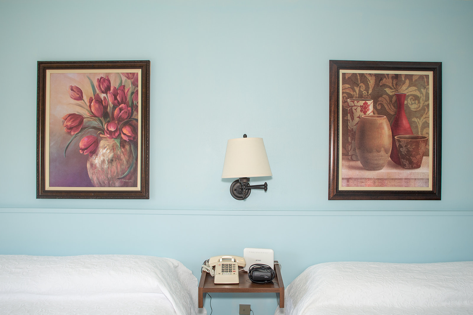 motel room with 2 beds. Paintings of red flowers hang on the walls