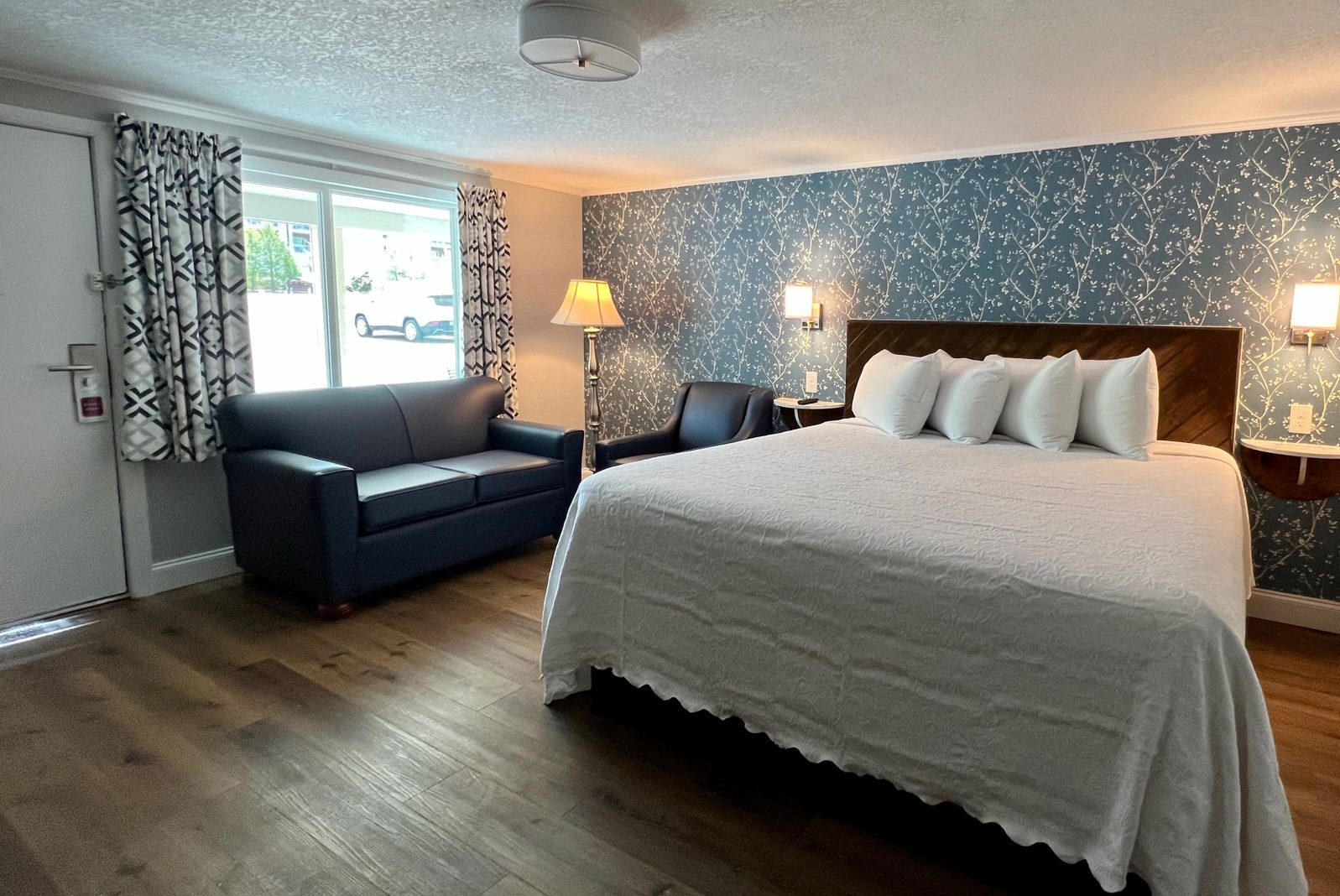 renovated deluxe single motel room with king size bed and blue wallpaper